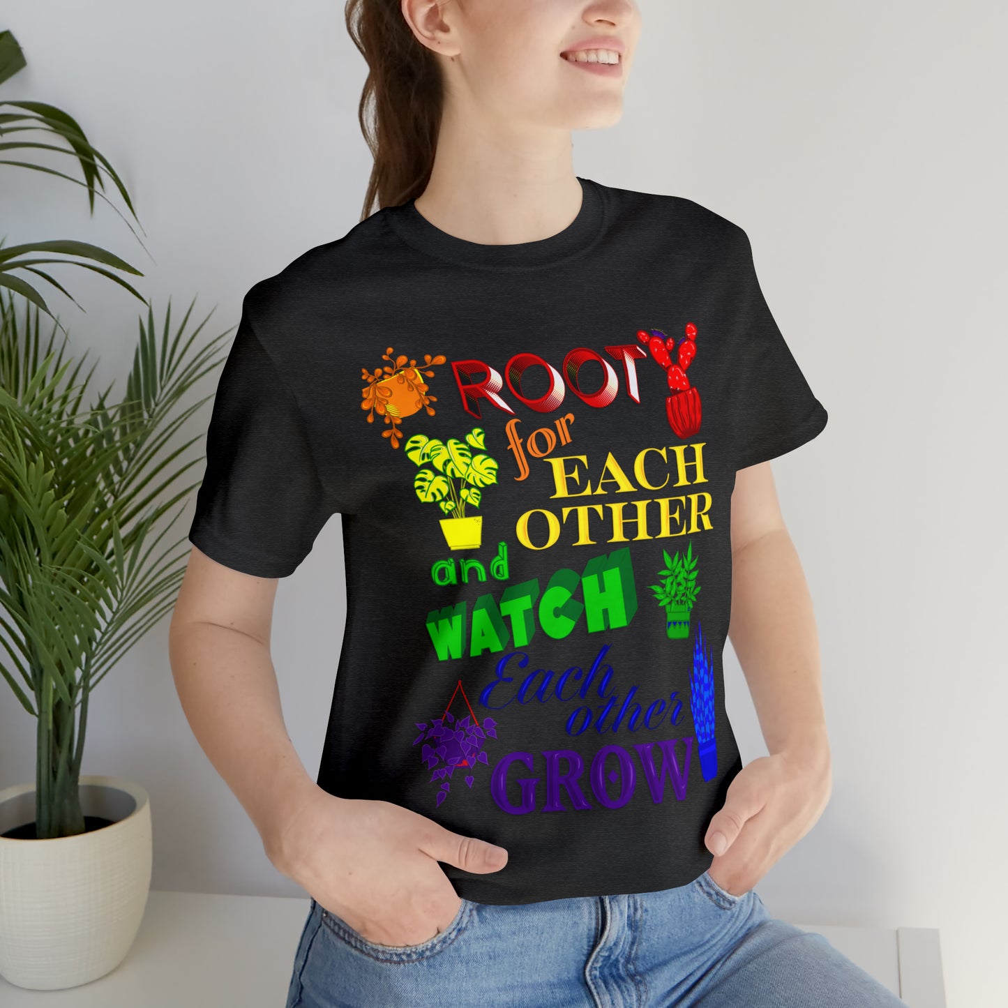 A vibrant t-shirt featuring a beautiful design of rainbow-colored plants. The phrase 'Root for each other and watch each other grow' is prominently displayed on the shirt. The design represents unity, support, and personal growth.