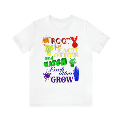 A vibrant t-shirt featuring a beautiful design of rainbow-colored plants. The phrase 'Root for each other and watch each other grow' is prominently displayed on the shirt. The design represents unity, support, and personal growth.