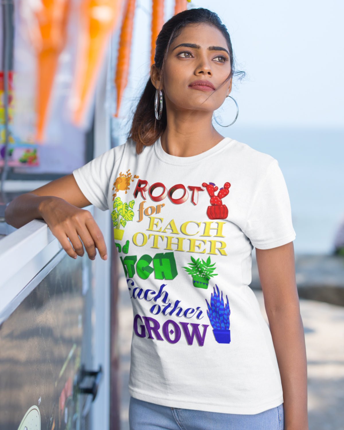 A vibrant t-shirt featuring a beautiful design of rainbow-colored plants. The phrase 'Root for each other and watch each other grow' is prominently displayed on the shirt. The design represents unity, support, and personal growth.